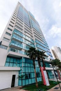 a tall building with palm trees in front of it at CONFORTO JH PALHANO, Ap 1507 in Londrina