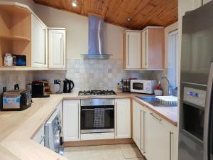 a kitchen with white cabinets and a stove top oven at Kingfisher Lodge - Uk46046 in Balloch