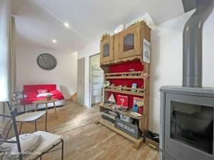 ein Wohnzimmer mit einem Kamin und einem roten Sofa in der Unterkunft Charme rustique près de Bagnoles, animaux admis, jardin et WiFi inclus - FR-1-497-222 in La Coulonche