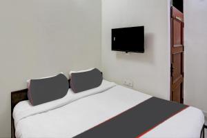 a bedroom with a bed with a tv on the wall at Hotel O Uk House Residency in Gurgaon