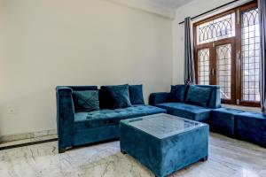 a living room with blue couches and a coffee table at Hotel O Uk House Residency in Gurgaon