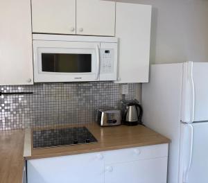 a white kitchen with a microwave and a stove at Prime and Precious location The Red House Room3 in Charlottetown