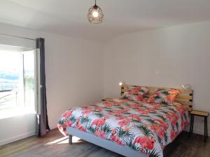a bedroom with a bed with a floral comforter at Gîte cosy avec cheminée, animaux acceptés et grande terrasse - FR-1-496-221 in Regny