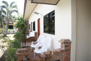 un patio con sillas blancas en una pared de ladrillo en Forum House Hotel Krabi, en Krabi
