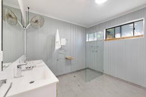 un bagno bianco con doccia e lavandino di Casuarina Cove - Foreshore Tropical Escape near CBD a Nightcliff Altre 18 foto