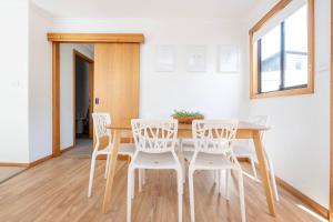 a dining room with a table and white chairs at Tasman Breeze - Beachside Escape near Historic Site in Port Arthur