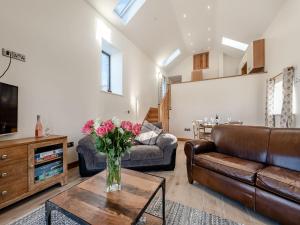 a living room with a couch and a vase of flowers on a table at Parlwr Godro - Uk41513 in Llanfair Clydogau