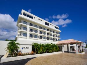 a large white building with palm trees in front of it at Lit Hotel NAKIJIN in Nakijin