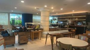 a restaurant with tables and chairs and a kitchen at Riviera de São Lourenço Boulevard Travel inn in Bertioga