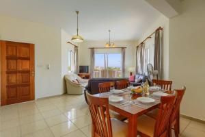 a dining room with a table and chairs and a living room at Villa Camelia by Villa Plus in Peyia