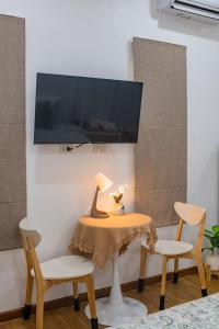 einen Tisch mit 2 Stühlen und einen TV an der Wand in der Unterkunft Sachi Minimal House Bangtao Beach - Near Muay Thai Gym in Ban Lum Fuang