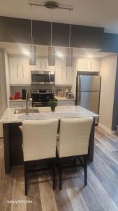 a kitchen with a sink and a counter with white chairs at One bedroom self contain in Prince Albert