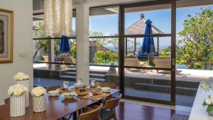 a dining room with a table and a large window at Villa Adenium by Elite Havens in Jimbaran