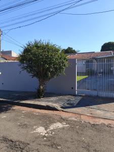 a white gate with a tree next to a building at Casa Tokio in Londrina