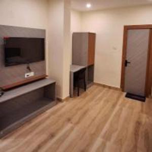 a living room with a television and a wooden floor at Aroma Prayagraj By StayApart in Prayagraj