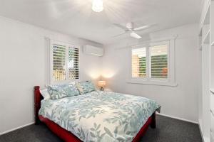 a bedroom with a bed with a ceiling fan and two windows at Gothic Pde 16, Currimundi in Kawana Waters