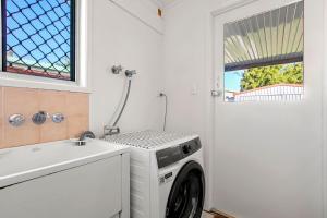 a laundry room with a washing machine and a sink at Gothic Pde 16, Currimundi in Kawana Waters