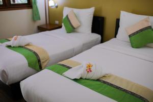 three beds in a room with white and green at Chareena Beachside in Ko Lipe