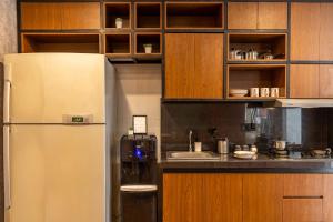 a kitchen with a white refrigerator and wooden cabinets at Cove Renata in Seminyak