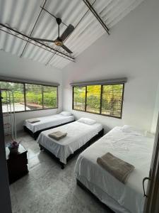 a bedroom with two beds and two windows at Finca Bello Terruño, Anapoima, Descanso, Naturaleza in Anapoima