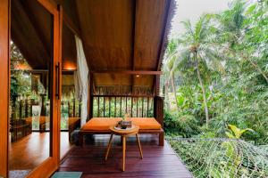 a room with a bench and a table on a porch at Ubud Jungle Stay by WAHM Hotel Management in Ubud +28 photos