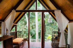 an open glass door to a porch with trees at Ubud Jungle Stay by WAHM Hotel Management in Ubud