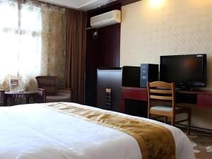 a hotel room with a bed and a desk and a television at Juntong Hotel in Bao'an