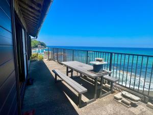 a picnic table on a balcony overlooking the beach at コンドミニアム海のまんまえ荘 in Ōda