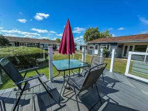 a patio with a table and chairs and an umbrella at Homely Chalet On A Brilliant Holiday Park In Lowestoft Ref 12004B in Lowestoft