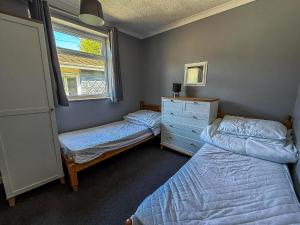 a bedroom with two beds and a dresser and a window at Homely Chalet On A Brilliant Holiday Park In Lowestoft Ref 12004B in Lowestoft
