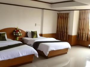 Un dormitorio con dos camas con sábanas blancas. en PC Palace Hotel, en Sakon Nakhon