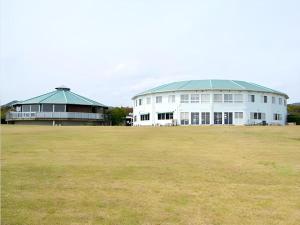ein großes weißes Gebäude mit einem grünen Dach auf einem Feld in der Unterkunft Nest West Garden Tosa Hotel in Kuroshio