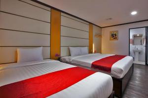 two beds in a hotel room with red and white sheets at Horizon Hotel in Olongapo