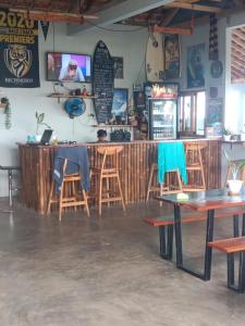a bar in a restaurant with wooden tables and chairs at AK's Surf Resort in Wainapal