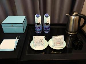 鄭州市にあるXana Hotelle Zhengzhou North Passenger Terminal North University Townのコーヒーメーカーとカップ2つ、ティーケトルが置かれたテーブル