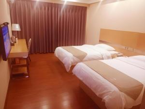 a hotel room with two beds and a desk and a television at GreenTree Inn Zhanjiang Haitian Bus Station in Zhanjiang