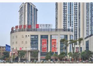 a building with red signs in front of tall buildings at Echarm Hotel Liuzhou High-speed Railway Station in Liuzhou