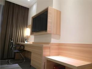 a room with a desk with a tv on a wall at City Comfort Inn Shenzhen Shiyan Science and Technology Park in Shenzhen
