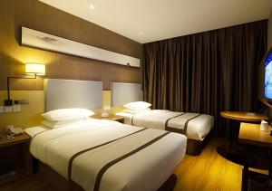 a hotel room with two beds and a flat screen tv at Jtour Inn Huanggang Wuxue City Square in Wuxue