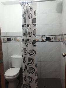 Un baño con inodoro y cortina de ducha. en Alojamiento Miller, en Ayacucho