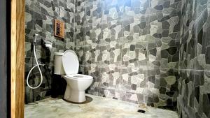 a bathroom with a toilet and a tiled wall at AK's Surf Resort in Wainapal