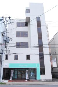a white building with lots of windows at 新潟駅徒歩7分 ペットと泊まれる宿 ベッド4台でゆったり宿泊 in Niigata
