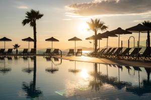 a pool with chairs and umbrellas on a beach at The Aeolos Beach Hotel in Kos Town