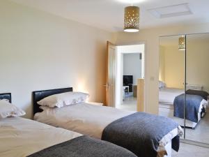 a bedroom with two beds and a mirror at Hornbeam Cottage in Great Malvern