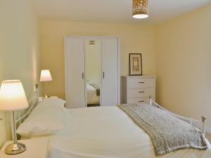 a bedroom with a white bed and a mirror at Hornbeam Cottage in Great Malvern