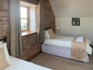 two beds in a room with a brick wall at Granary in North Somercotes