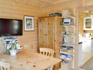 a dining room with a wooden table and a television at Forest Lodge in Godshill