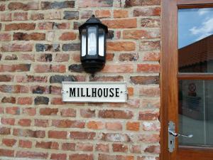 a sign on a brick wall with a mill house sign at Mill House in North Somercotes +6 photos