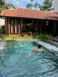 un hombre con una tabla de surf en una piscina en DeMin Villa Hội An - Pool and BBQ Garden, en Hoi An