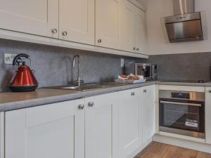 a kitchen with white cabinets and a tea kettle on the counter at Coast Apartment in Whitby